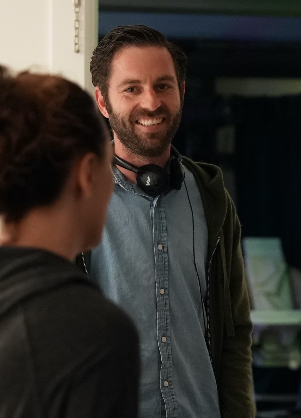 Dan Levy Dagerman on set, smiling, with headphones around his neck